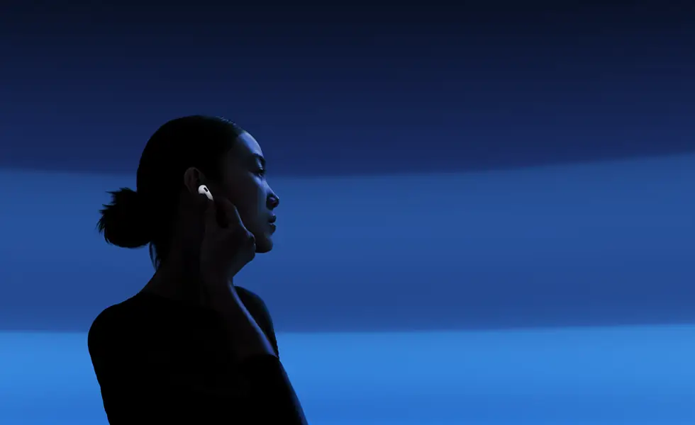 Une personne tenant la tige de ses AirPods 5 entre le pouce et l’index pour changer les modes d’écoute