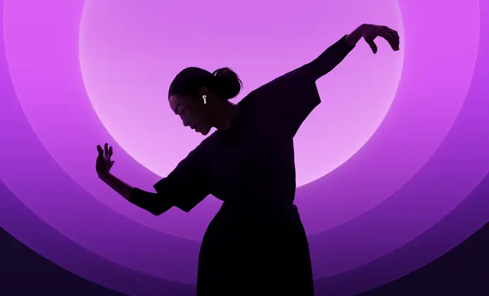 Une personne danse avec ses AirPods 5 aux oreilles, sur fond multicolore
