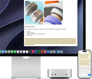 Mac mini de face, glissé sous un Studio Display, un iPhone se trouve à droite de l’appareil et de l’écran, du texte sélectionné avec les commandes Couper, Copier, Coller et Remplissage automatique en haut de l’iPhone correspond au texte surligné à l’écran, illustrant le fonctionnement du presse-papiers universel